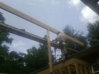 Carpenter setting a ridge beam over a new addition frame — Ice Dam Removal by Roofing Brothers in Woodburn