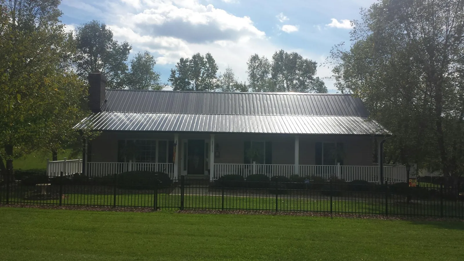 Gray metal roof on a brick ranch with a full width front porch — Gutter Guard Installation work by our crew in Woodburn